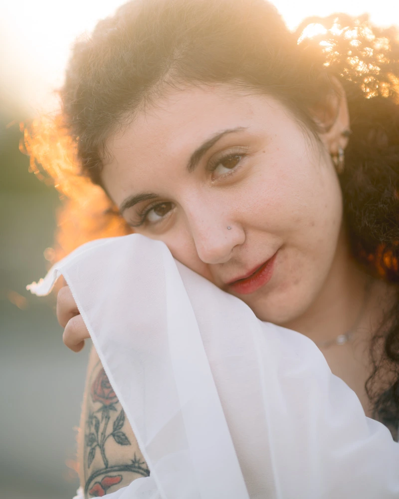 Gros plan d'un portrait de femme aux cheveux bouclés tenant un voile blanc sous la lumière dorée du coucher de soleil à Ruffec en Charente par Alexandre Topolewski