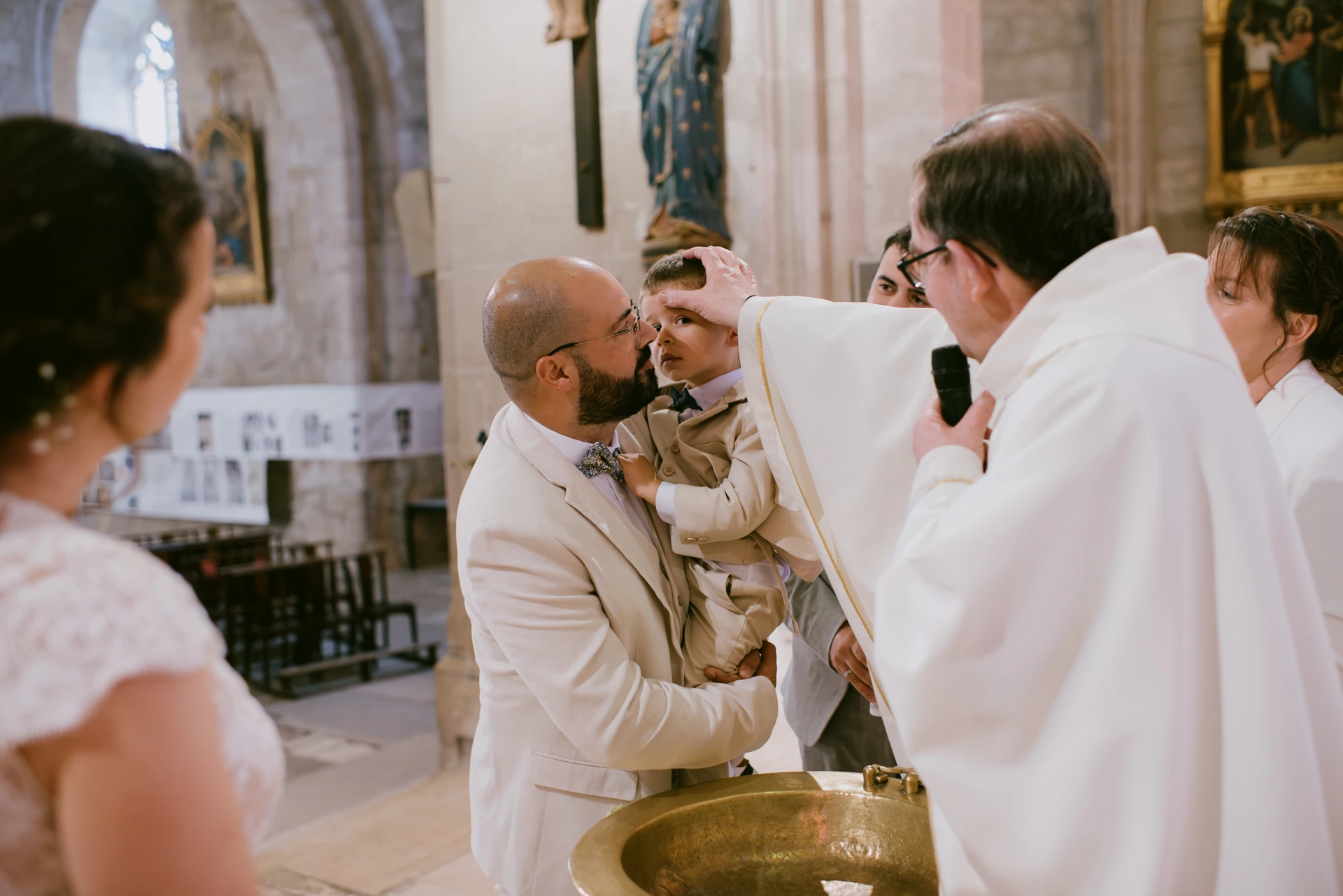 Prêtre versant l'eau sainte sur un enfant, baptême à Ruffec par Alexandre Topolewski