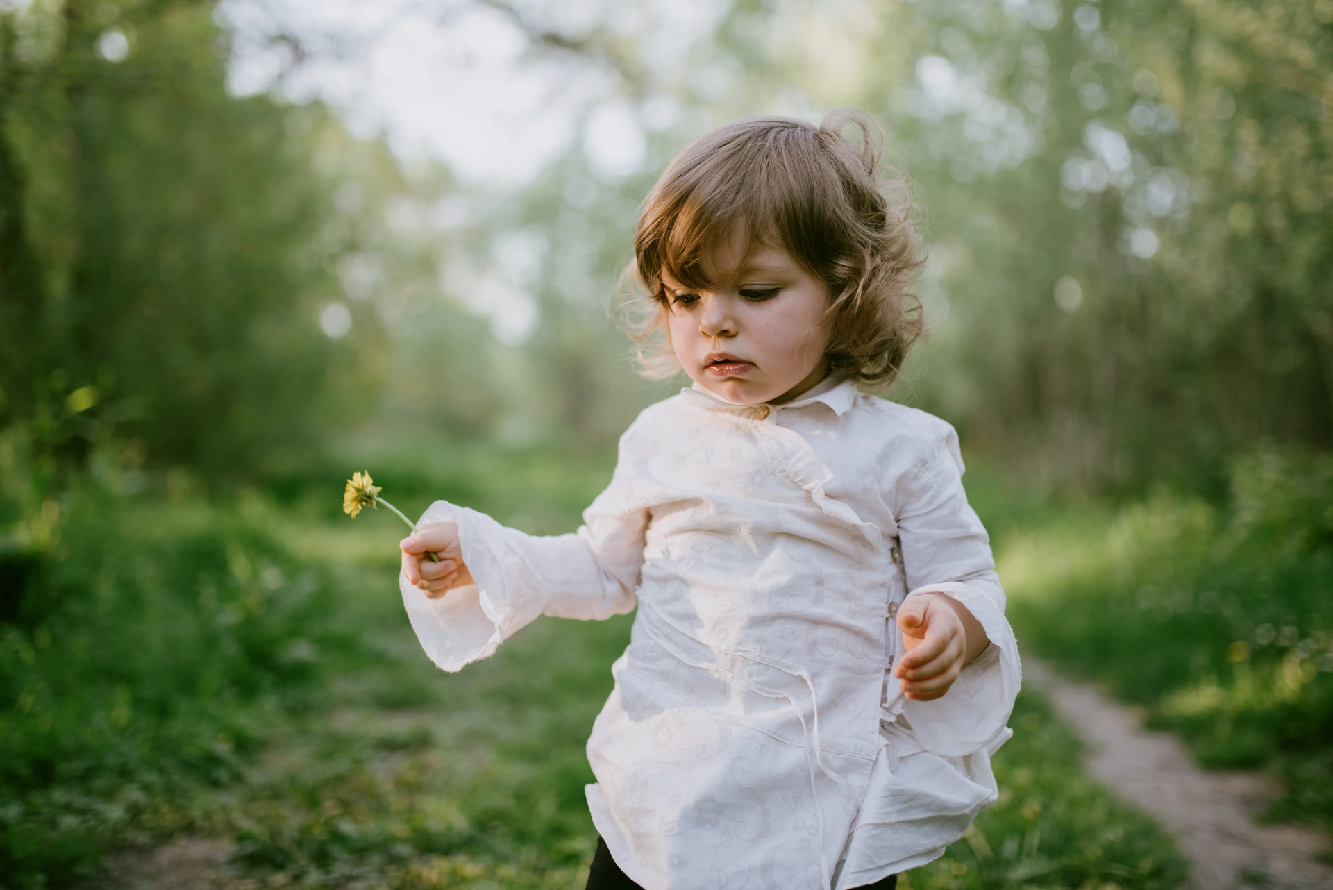 Enfant en blouse blanche tenant une fleur jaune, séance photo famille à Saint-Yrieix-sur-Charente par Alexandre Topolewski