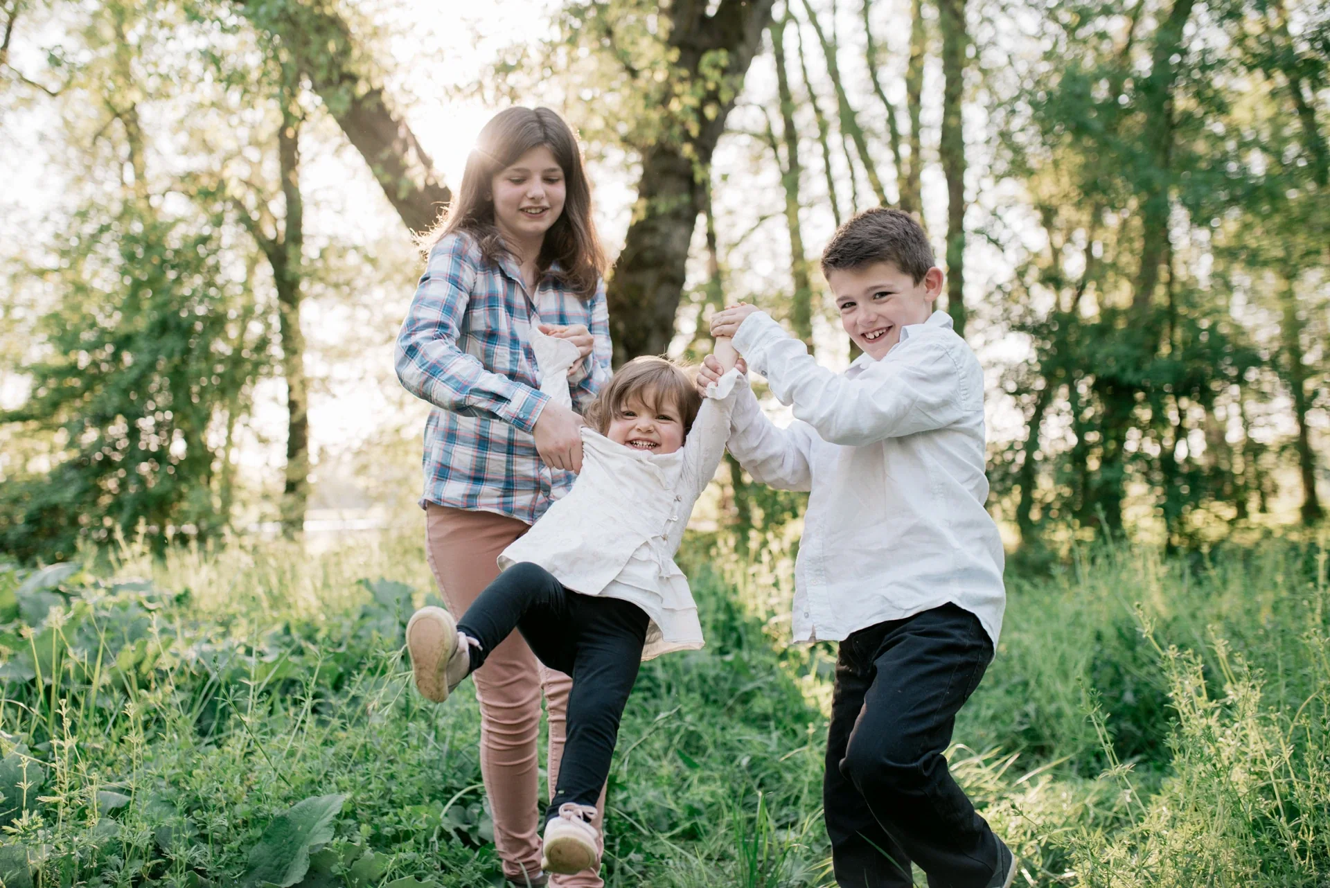 Fratrie soulevant leur petite sœur, séance photo famille à Saint-Yrieix-sur-Charente par Alexandre Topolewski