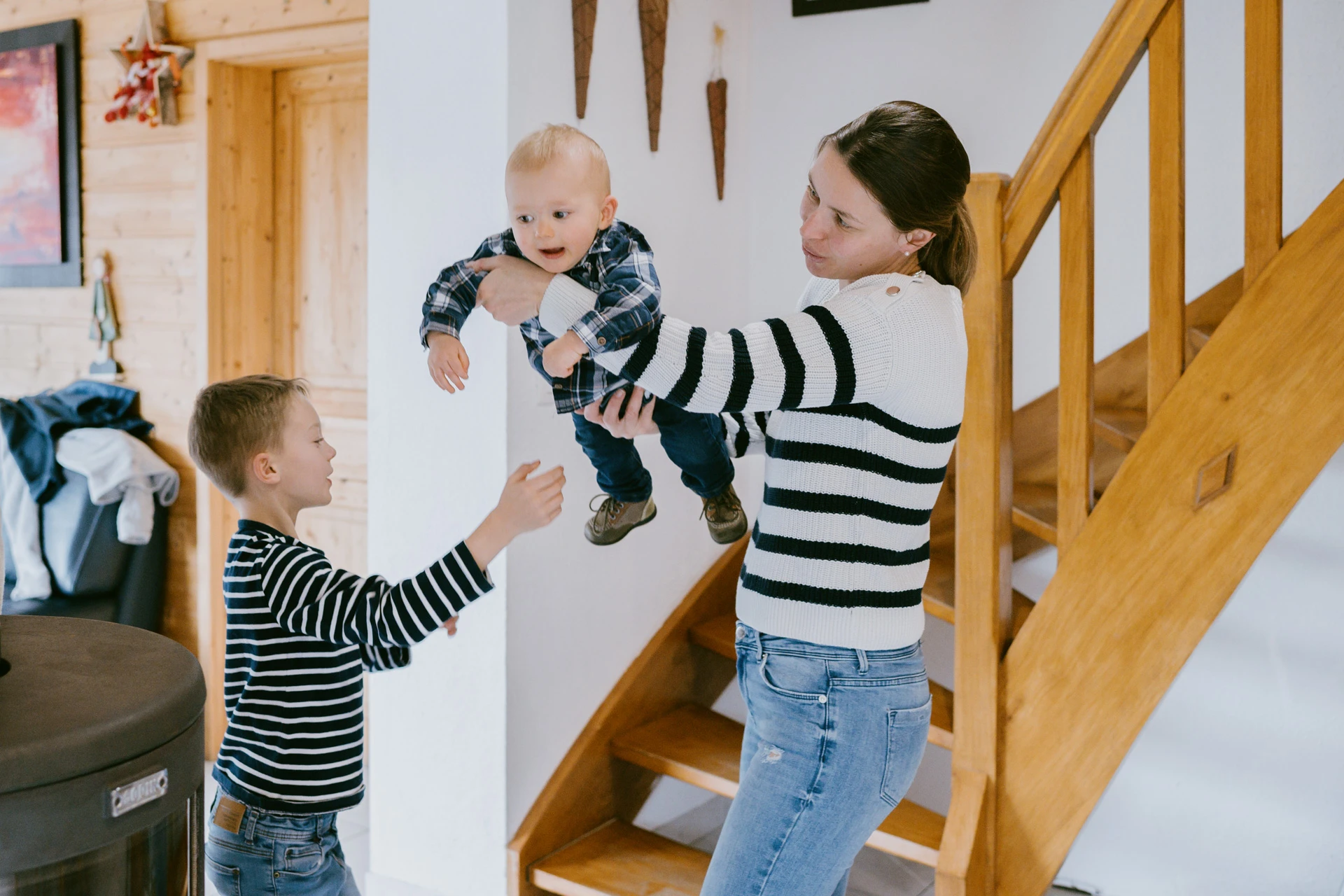 Mère soulevant son bébé près d’un escalier en bois, séance photo famille à Tusson par Alexandre Topolewski