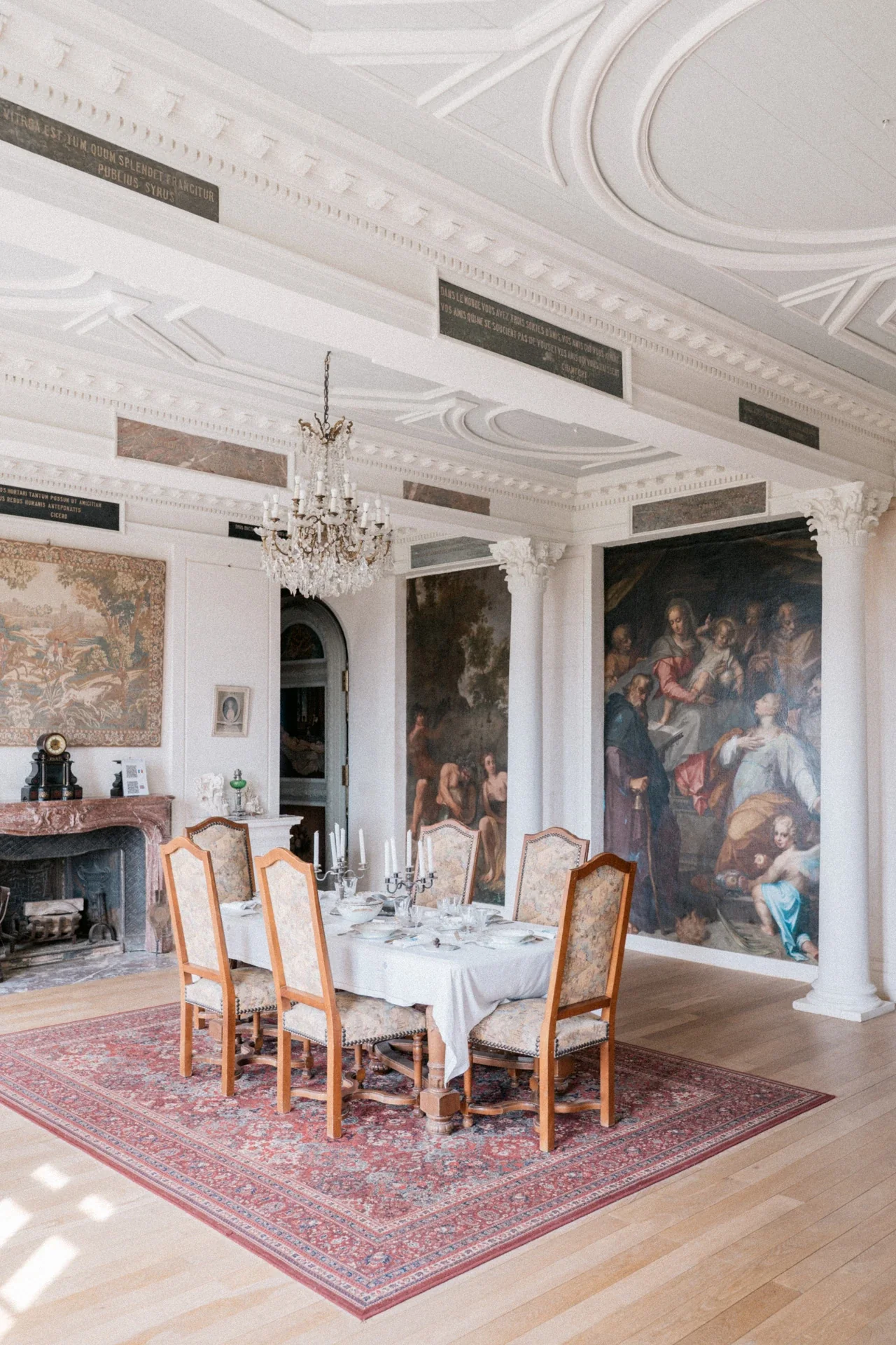 Salle à manger aux plafonds moulurés, lustre à pampilles, colonnes corinthiennes et grandes peintures murales