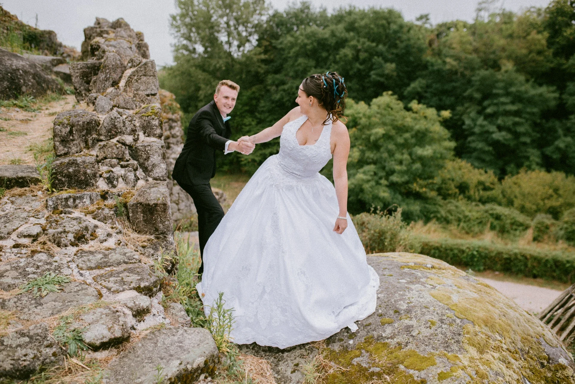 Le marié tendant la main à la mariée pour l’aider à gravir les rochers des ruines