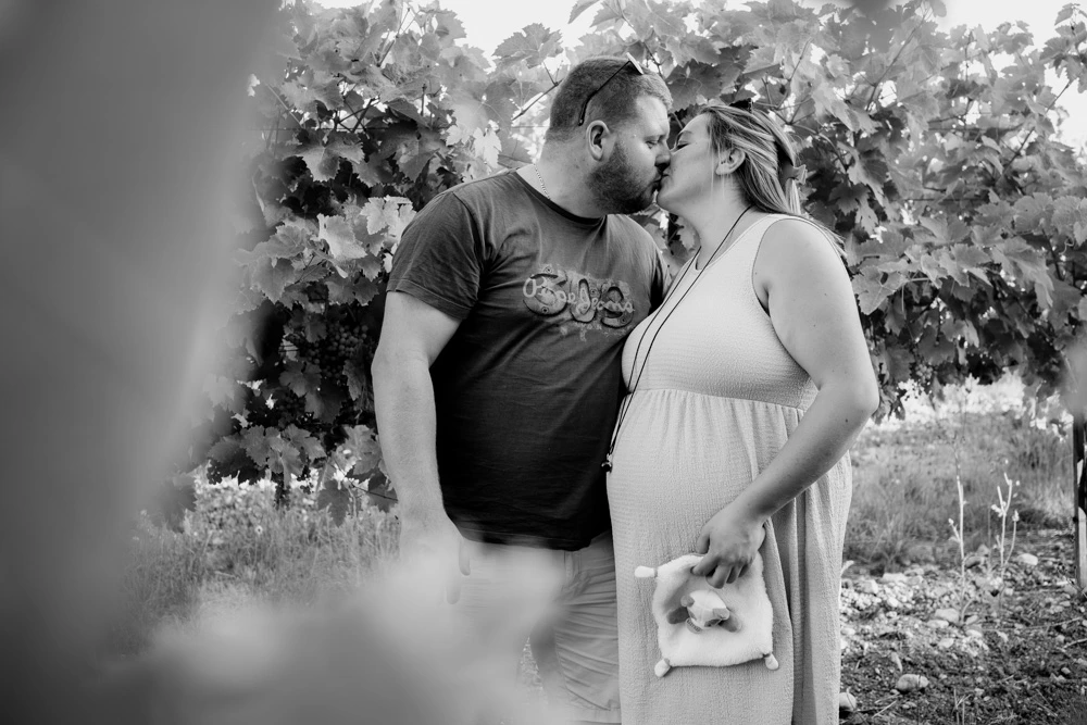 Baiser du couple dans les vignes, doudou tenu à la main, en noir et blanc