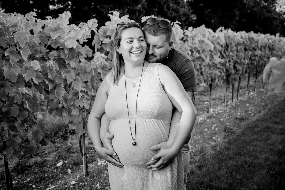 Câlin du couple dans les vignes, la future maman éclate de rire, en noir et blanc