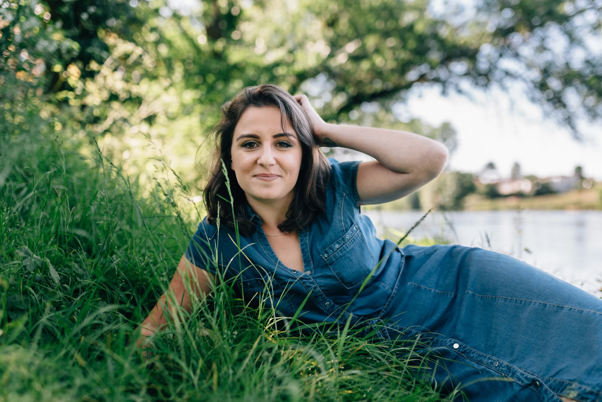 Portrait d'une femme allongée dans l'herbe haute au bord de l'eau en Charente, en robe en jean, par Alexandre Topolewski