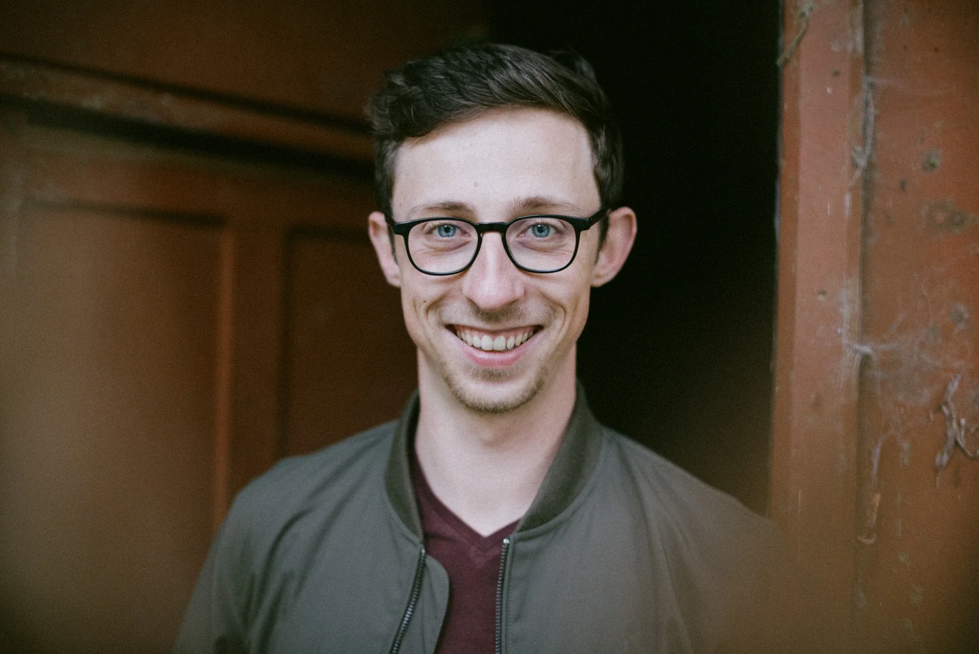 Portrait lifestyle d'un jeune homme souriant avec des lunettes et les yeux bleus à La Chapelle par Alexandre Topolewski