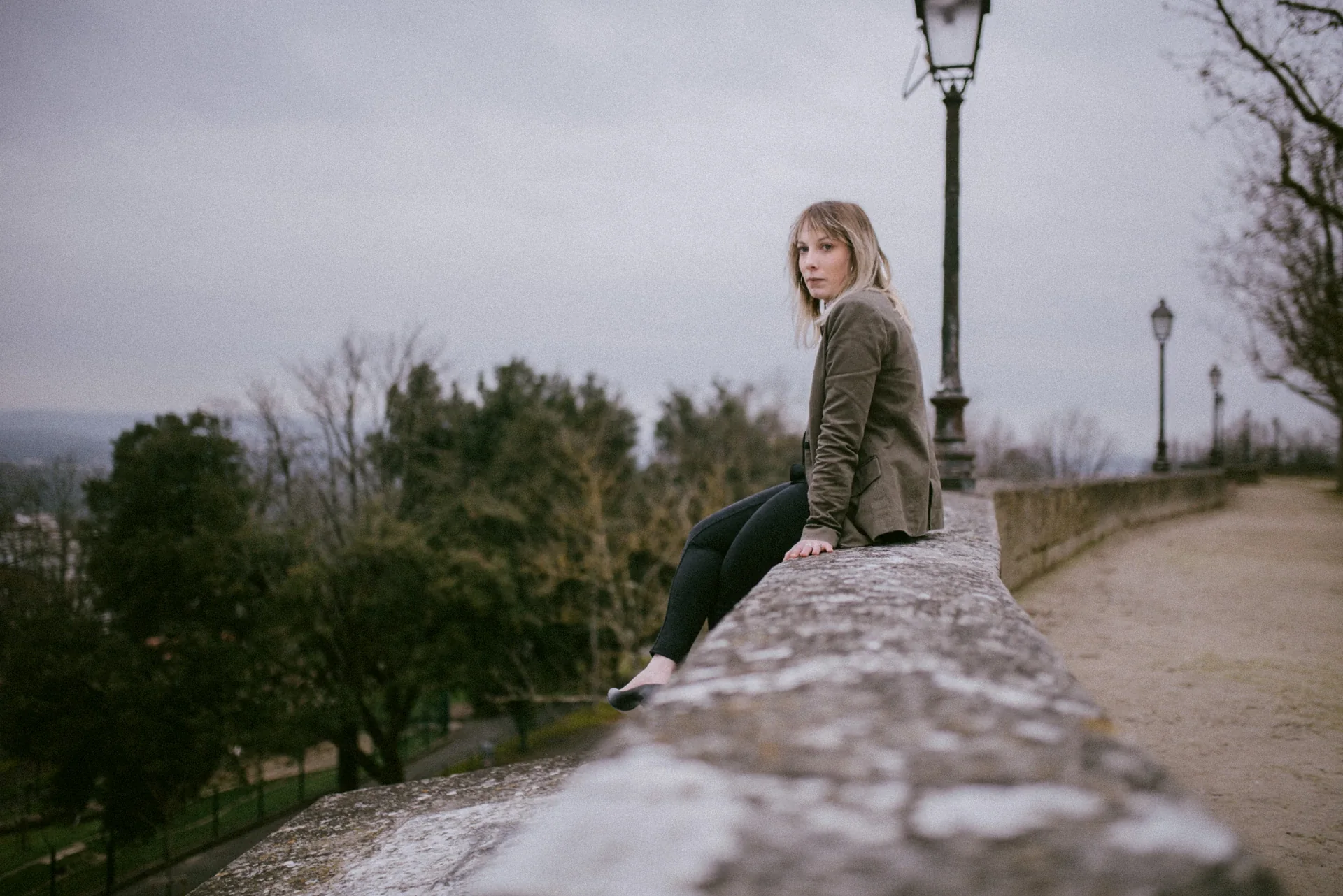 Portrait lifestyle d'une femme blonde assise sur le muret des remparts d'Angoulême par Alexandre Topolewski