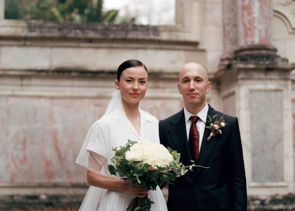 Portrait des mariés devant une architecture en pierre, photographie de mariage argentique au Château du Taillan, Bordeaux