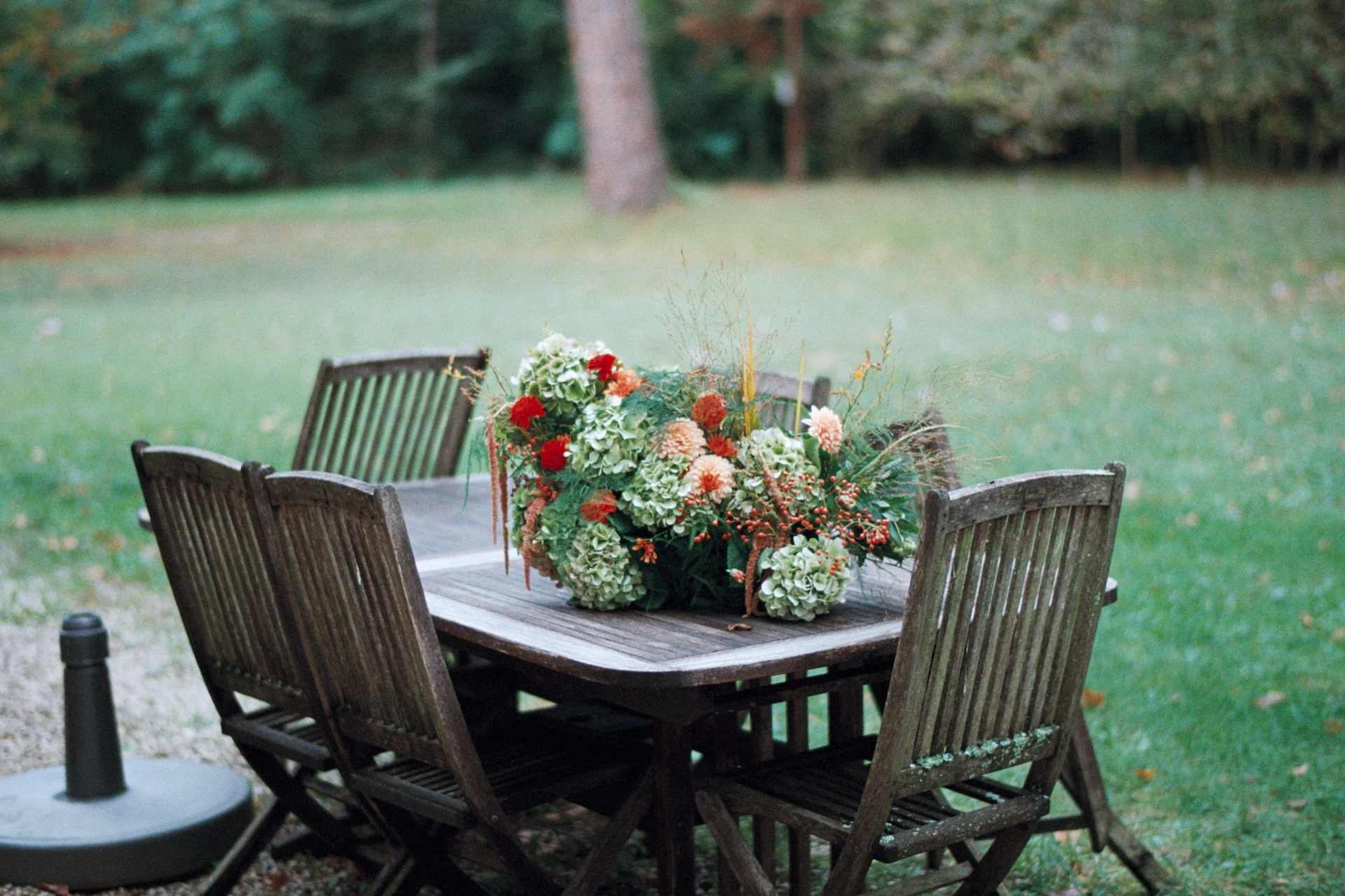 Détail de décoration florale de table de mariage en extérieur, style champêtre, prise de vue argentique.