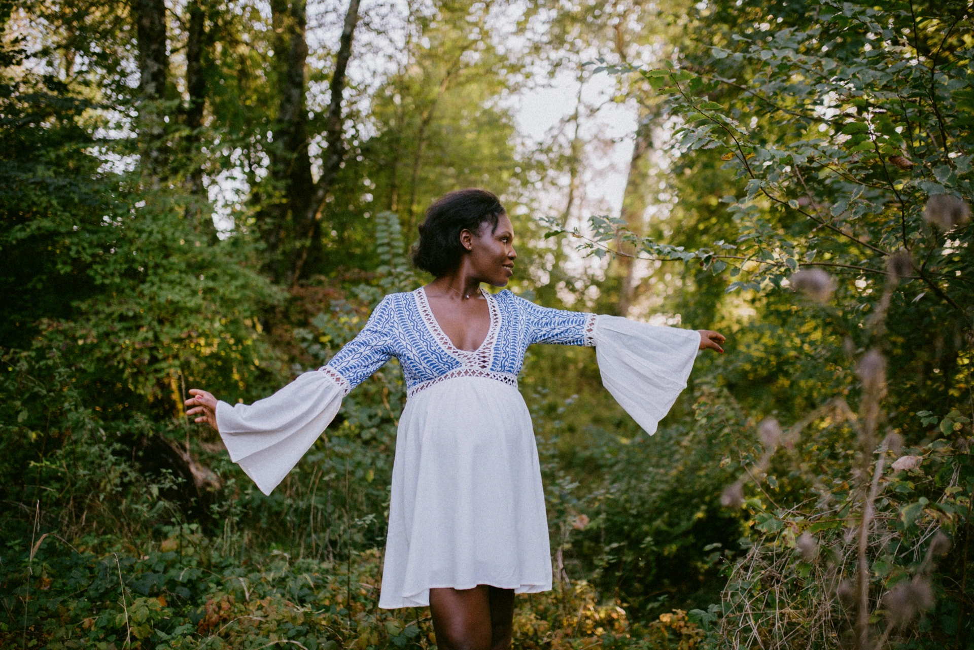 Femme enceinte de dos dans les bois, robe fluide, photographe maternité Angoulême