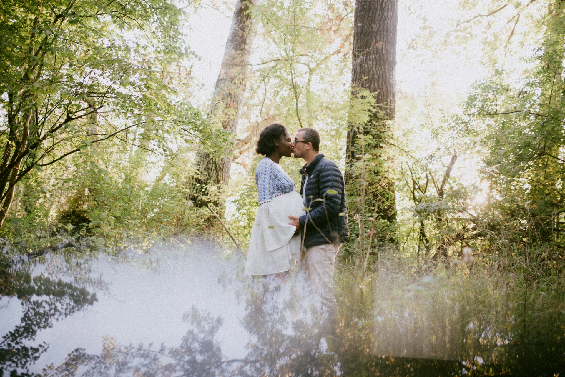 Couple s'embrassant en forêt avec effet de reflet créé au smartphone, photographe grossesse Angoulême
