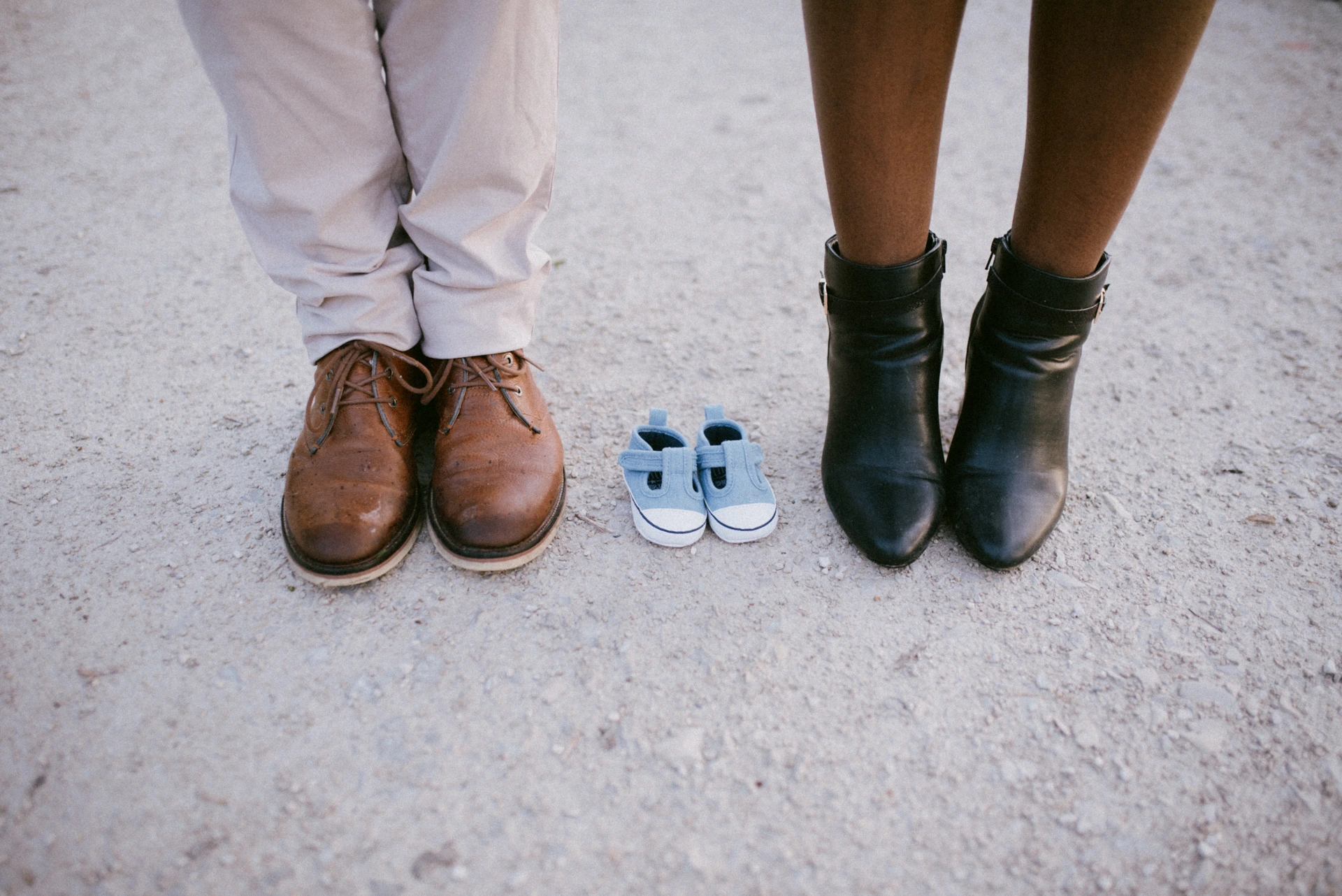 Chaussures des futurs parents avec de petits chaussons de bébé entre les deux, annonce grossesse Charente