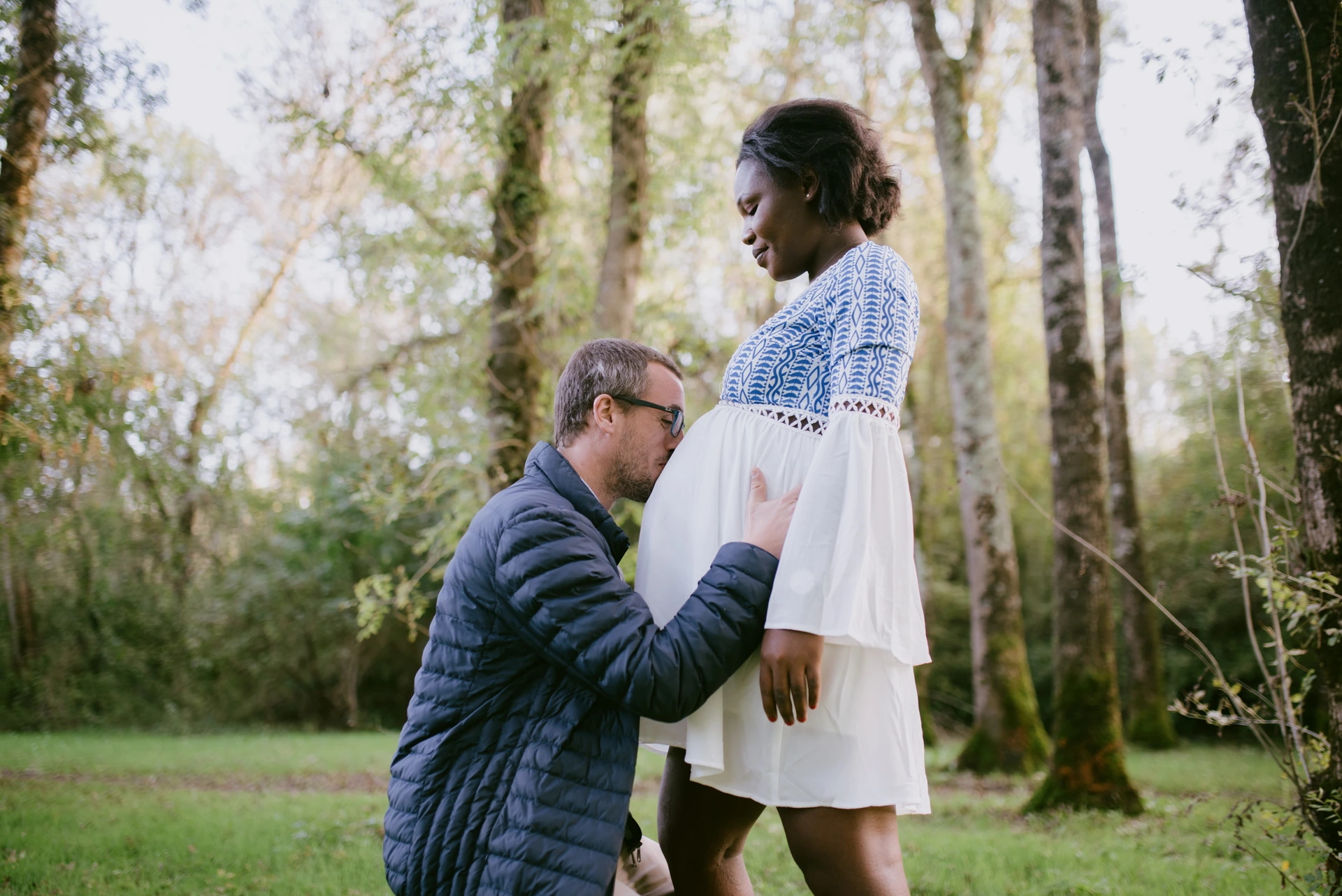 Futur père embrassant le ventre de sa compagne enceinte en forêt, photographe grossesse Saint-Yrieix Charente